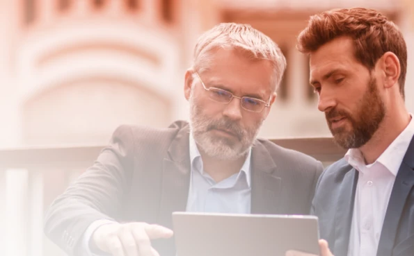 Two professionals collaborate and analyse data on a digital device.